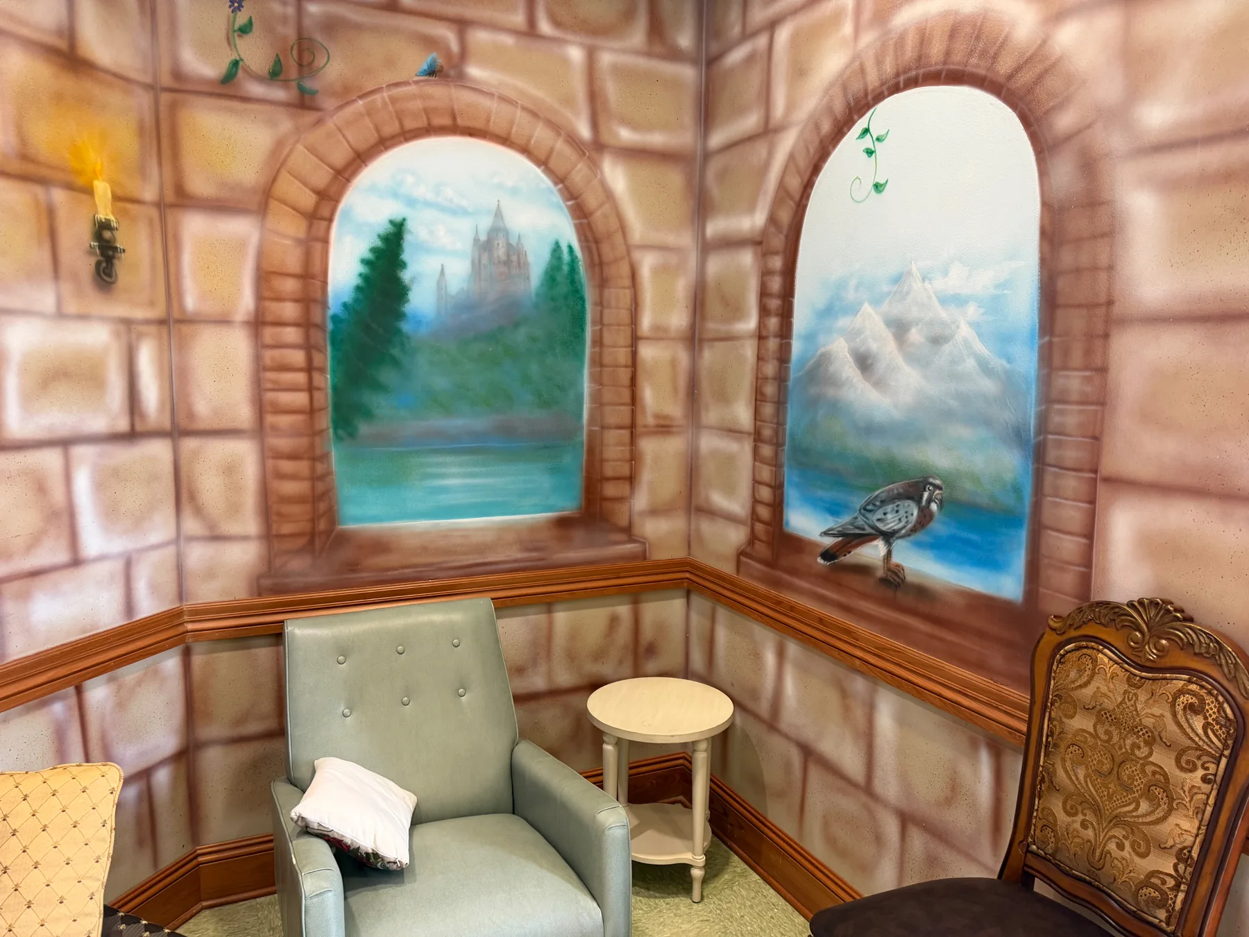 The castle-themed waiting nook at Preferred Pediatrics, with painted stone windows looking out on a castle and mountains