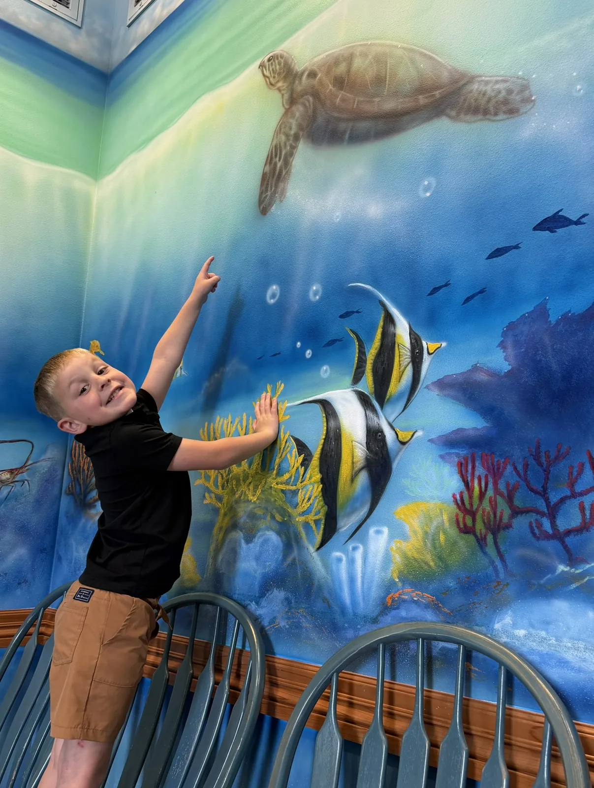 A young patient exploring the hand-painted undersea mural in the ocean room at Preferred Pediatrics