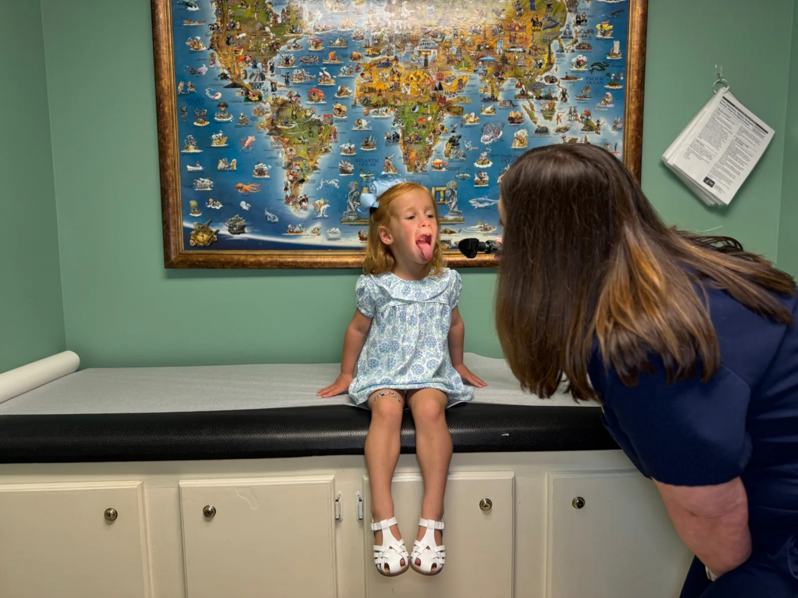 A Preferred Pediatrics nurse checks a young patient's throat and ears with an otoscope during a same-day sick visit in Thibodaux, LA