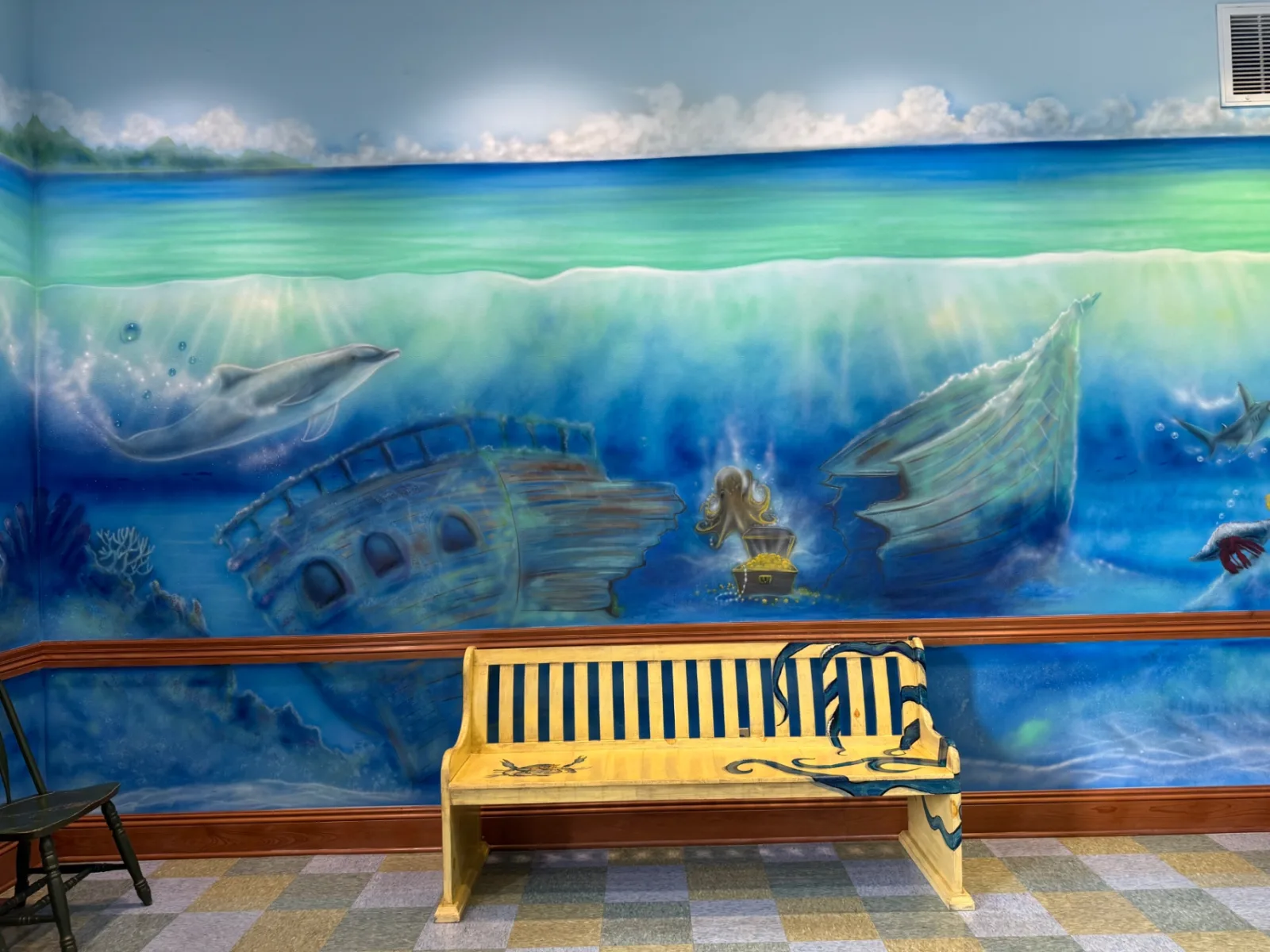 A hand-painted wooden bench with an octopus illustration sits in the ocean-themed waiting area at Preferred Pediatrics in Thibodaux