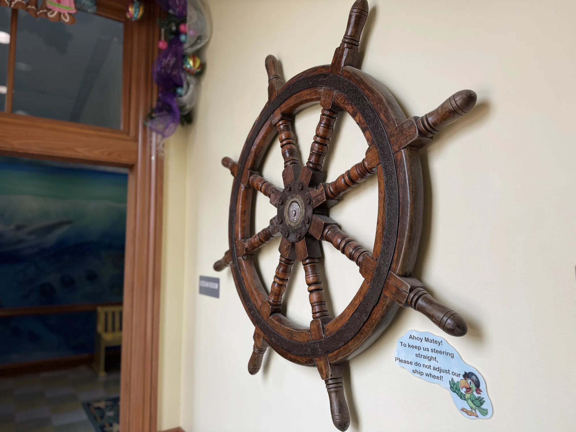 Decorative wooden ship's wheel mounted in the ocean-themed waiting room