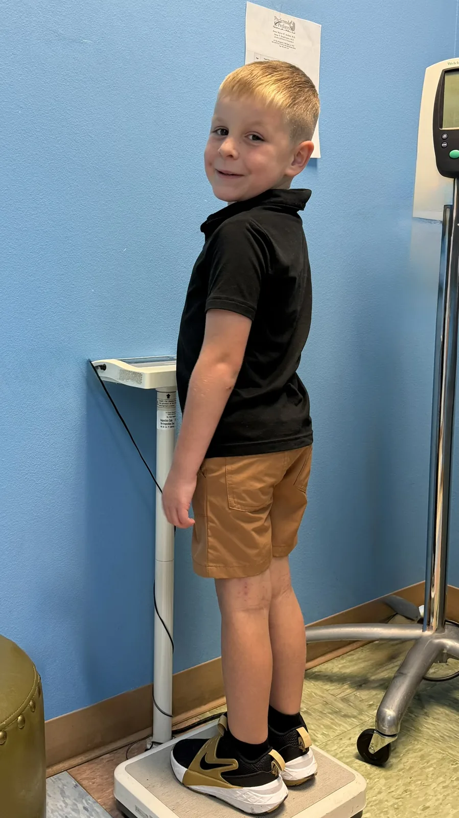 A young patient standing on the scale for a height and weight check during a well-child visit at Preferred Pediatrics