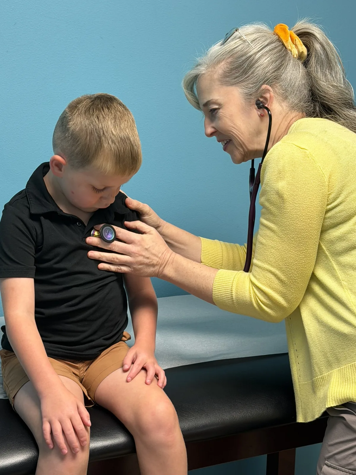Provider listening to a young patient's heart with a stethoscope during a wellness visit